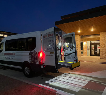 A van parked at night, featuring a wheelchair positioned beside it