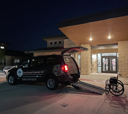 A van parked in front of a building, featuring a wheelchair positioned nearby for accessibility